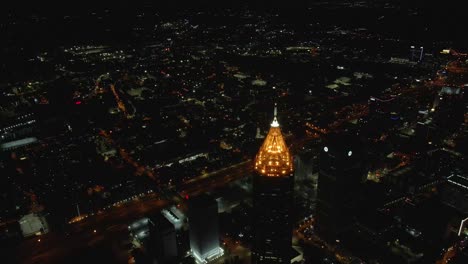 An-approaching-drone-shot-of-a-lit-up-skyscraper-downtown