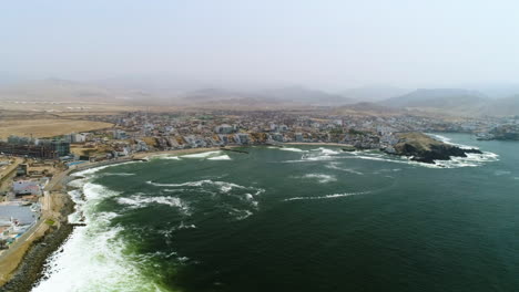 Drone-pull-back-away-from-the-coastline-of-San-Bartolo,-on-a-hazy-day-in-Peru