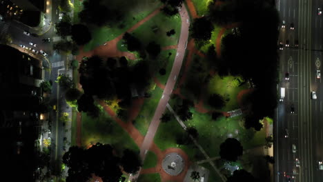 Nächtliche-Luftaufnahme:-Draufsicht-Auf-Den-Park,-Umgeben-Von-Straßen-Mit-Verkehr