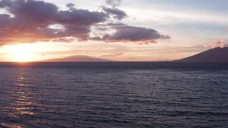 Low-panning-aerial-shot-of-Lanai-and-West-Maui-at-sunset-from-Wailea-in-South-Maui,-Hawai'i