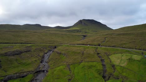Dolly-in-towards-cars-driving-on-Faroe-Islands-street-during-road-trip-near-Kvivik