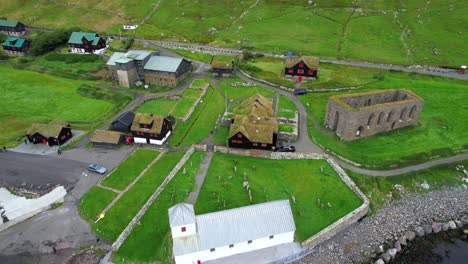 Aerial-pan-of-St-Olav-Church-and-St-Magnus-Cathedral-ruins-near-turf-roof-houses,-Kirkjubour