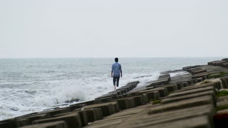 Man-Is-Walking-Alone-Over-Block-Concrete-Sea-Walls-With-Rough-Waves