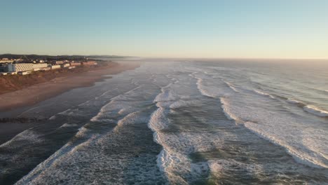 Hazy-evening-aerial-of-waves-coming-into-beach,-Oregon-coast