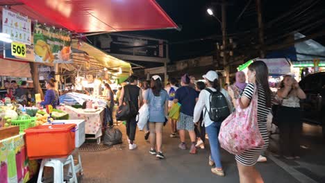 Compradores-Locales-Y-Extranjeros-Llevando-Sus-Bolsas-De-Compras-Llenas-De-Artículos-Comprados-En-El-Mercado-Nocturno-De-Fin-De-Semana-De-Chatuchak,-Un-Famoso-Centro-Comercial-En-Bangkok,-Tailandia.