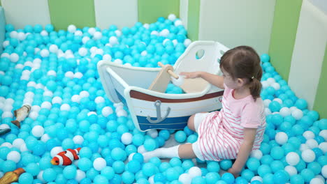 Preschooler-Girl-in-Playroom-Dry-Paddling-Pool-Playing-with-White-and-Blue-Balls