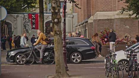 Man-on-bike-cycling-over-road-in-slow-motion-in-beautiful-Amsterdam,-the-Netherlands