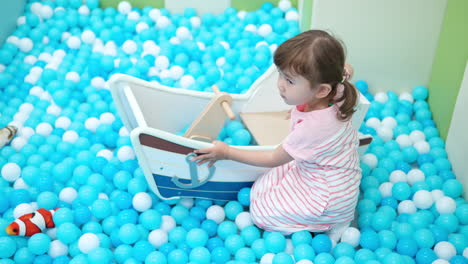 Süßes-Kleines-Mädchen,-Das-Auf-Bunten-Plastikbällen-Im-Großen,-Trockenen-Planschbecken-Im-Spielzentrum-Spielt