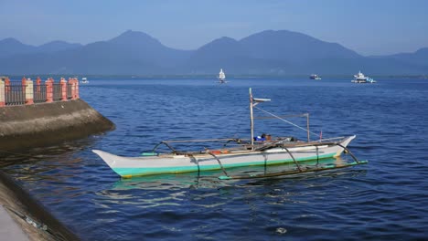 Pervasive-blue-hue-under-the-early-morning-sun-greets-small-fishing-boat-moored-at-the-shore-of-Puerto-Princesa-City,-capital-of-Palawan,-Philippines