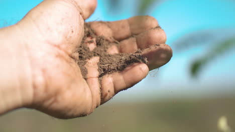 Hand-releasing-soil,-symbolizing-the-connection-between-humanity-and-the-earth,-and-the-act-of-nurturing-the-land