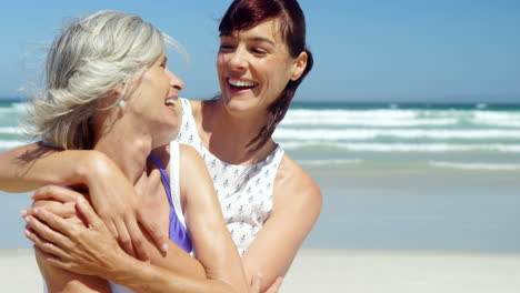 Mother-and-daughter-embracing-each-other-at-beach
