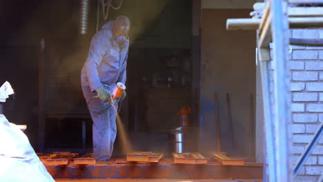 Metalsmith-using-spray-painting-machine-in-workshop-4k