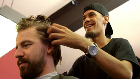 Man-interacting-with-barber-while-trimming-his-hair-4k