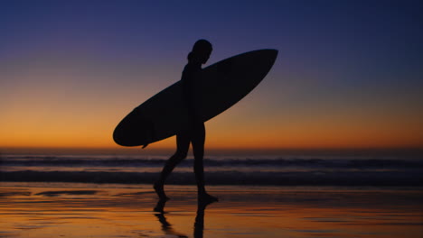 Surfista-Femenina-Caminando-Con-Tabla-De-Surf-En-La-Playa-4k