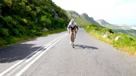 Ciclista-Femenina-En-Bicicleta-Por-Un-Camino-Rural-Al-Lado-De-Una-Montaña-Exuberante-4k