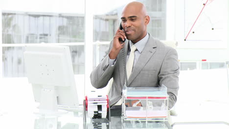 Ethnic-business-man-on-phone-working-at-a-computer