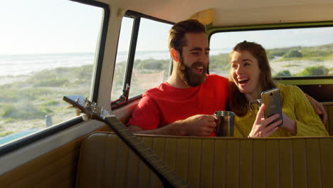 Happy-couple-using-mobile-phone-in-the-van-4k