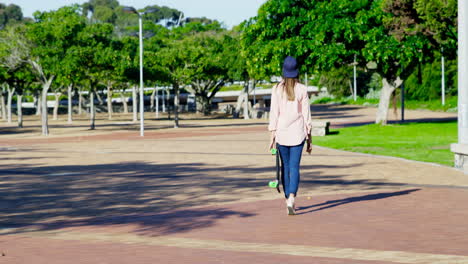 Woman-with-skate-board-walking-in-the-park-4k