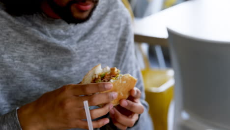 Hombre-Comiendo-Hamburguesa-En-Café-4k