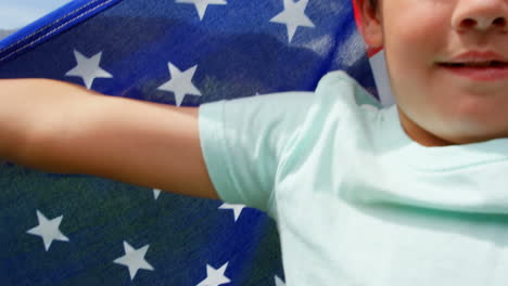 Front-view-of-Caucasian-schoolboy-holding-American-flag-in-school-playground-4k