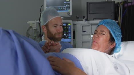 Front-view-of-Caucasian-man-comforting-pregnant-woman-during-labor-in-operation-theater-at-hospital-