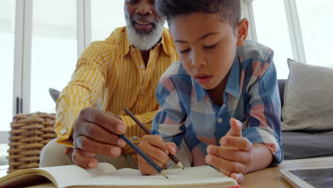Front-view-of-mature-black-father-helping-his-son-with-homework-in-a-comfortable-home-4k