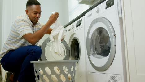 Side-view-of-mid-adult-black-man-washing-clothes-in-washing-machine-at-comfortable-home-4k