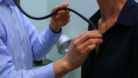 Mid-section-of-male-doctor-examining-a-senior-patient-with-stethoscope-in-the-clinic-4k