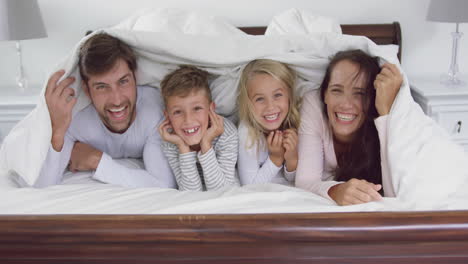 Familie-Liegt-Zusammen-Unter-Einer-Decke-Im-Schlafzimmer-Zu-Hause-4k