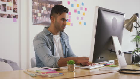 Mixed-race-man-working-on-computer-in-creative-office