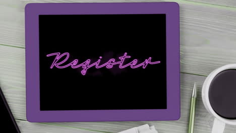Animation-of-pink-neon-style-word-Register-flickering-on-screen-of-digital-tablet-put-on-desk