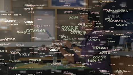 Animation-of-COVID-19-and-VIRUS-words-moving-over-an-Asian-man-working
