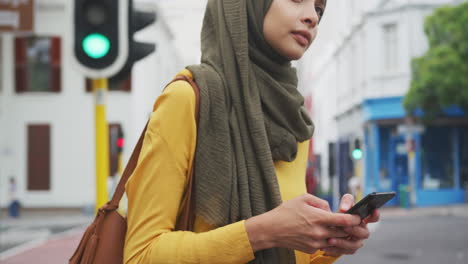 Woman-wearing-hijab-holding-her-phone-in-the-street