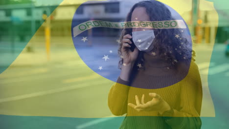 Bandera-Brasileña-Ondeando-Contra-Una-Mujer-Con-Mascarilla-Hablando-Por-Teléfono-Inteligente