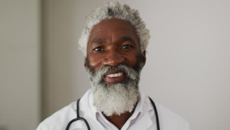 Porträt-Eines-Afroamerikanischen-Leitenden-Männlichen-Arztes-Mit-Weißem-Haar-Und-Bart,-Der-In-Die-Kamera-Lächelt