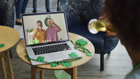 Man-having-beer-on-laptop-video-call-celebrating-st-patrick's-day-with-friends