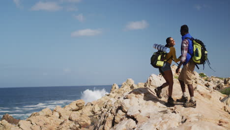 African-american-couple-climbing-on-the-rocks-while-trekking