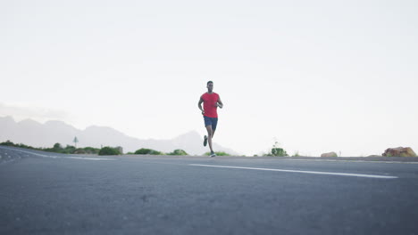 African-american-man-wearing-sportswear-running-on-the-road