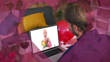 Heart-shaped-cutout-against-caucasian-man-waving-while-having-a-video-call-on-laptop