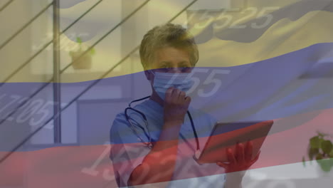 Animation-of-flag-of-colombia-and-statistics-with-female-doctor-with-tablet-taking-off-mask