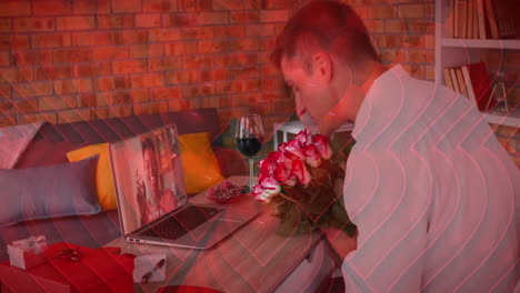Rote-Herzsymbole-über-Einem-Kaukasischen-Mann,-Der-Einen-Blumenstrauß-Hält,-Während-Er-Einen-Videoanruf-Auf-Dem-Laptop-Führt