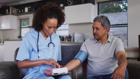 Senior-mixed-race-man-with-female-doctor-home-visiting-taking-blood-pressure
