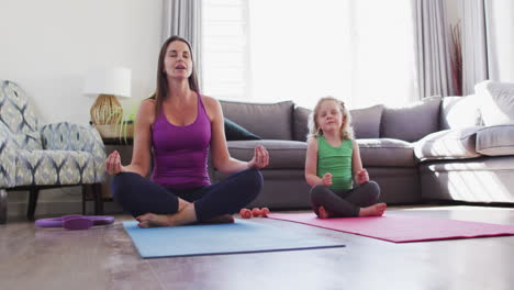 Caucasian-mother-and-daughter-having-fun-meditating-in-living-room