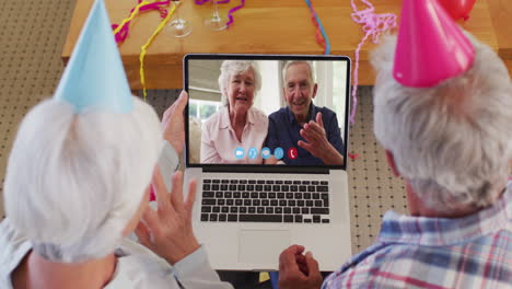 Kaukasisches-älteres-Paar-Mit-Partyhüten-Auf-Laptop-Videochat-Während-Weihnachten-Zu-Hause