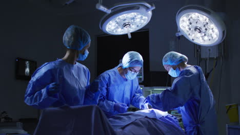 Diverse-surgeons-wearing-surgical-caps-and-face-masks-in-operating-theatre-in-hospital