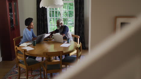 Afroamerikanisches-Paar-Sitzt-Am-Esstisch-Und-Benutzt-Laptops,-Um-Rechnungen-Zu-Bezahlen