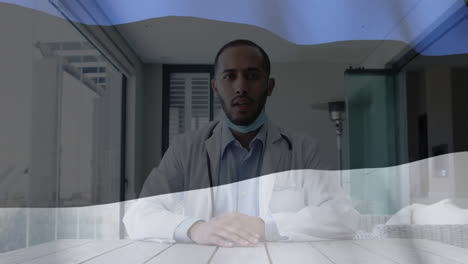 Animation-of-flag-of-estonia-with-masked-male-doctor-at-desk-giving-video-consultation