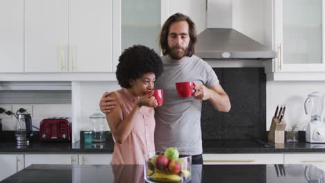 Mixed-race-couple-drinking-coffee-together-in-the-kitchen-at-home