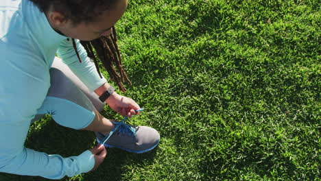 African-american-woman-in-sportswear-tying-her-shoelaces-in-park