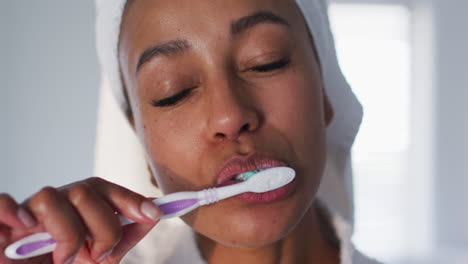 Porträt-Einer-Afroamerikanischen-Frau-Im-Bademantel,-Die-Sich-Im-Badezimmer-Die-Zähne-Putzt